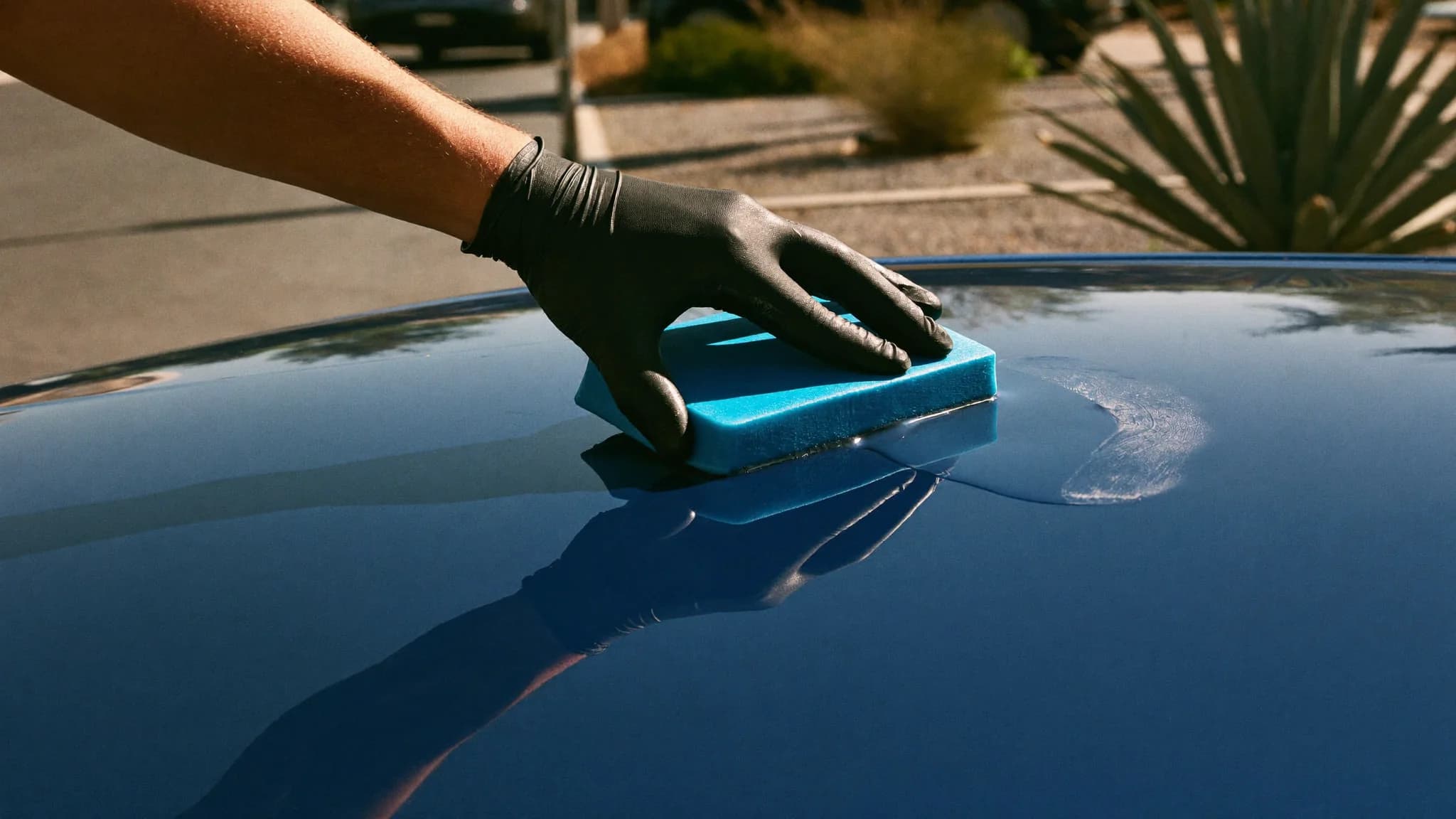 Detailer using a clay bar treatment on a car hood in a Las Vegas driveway
