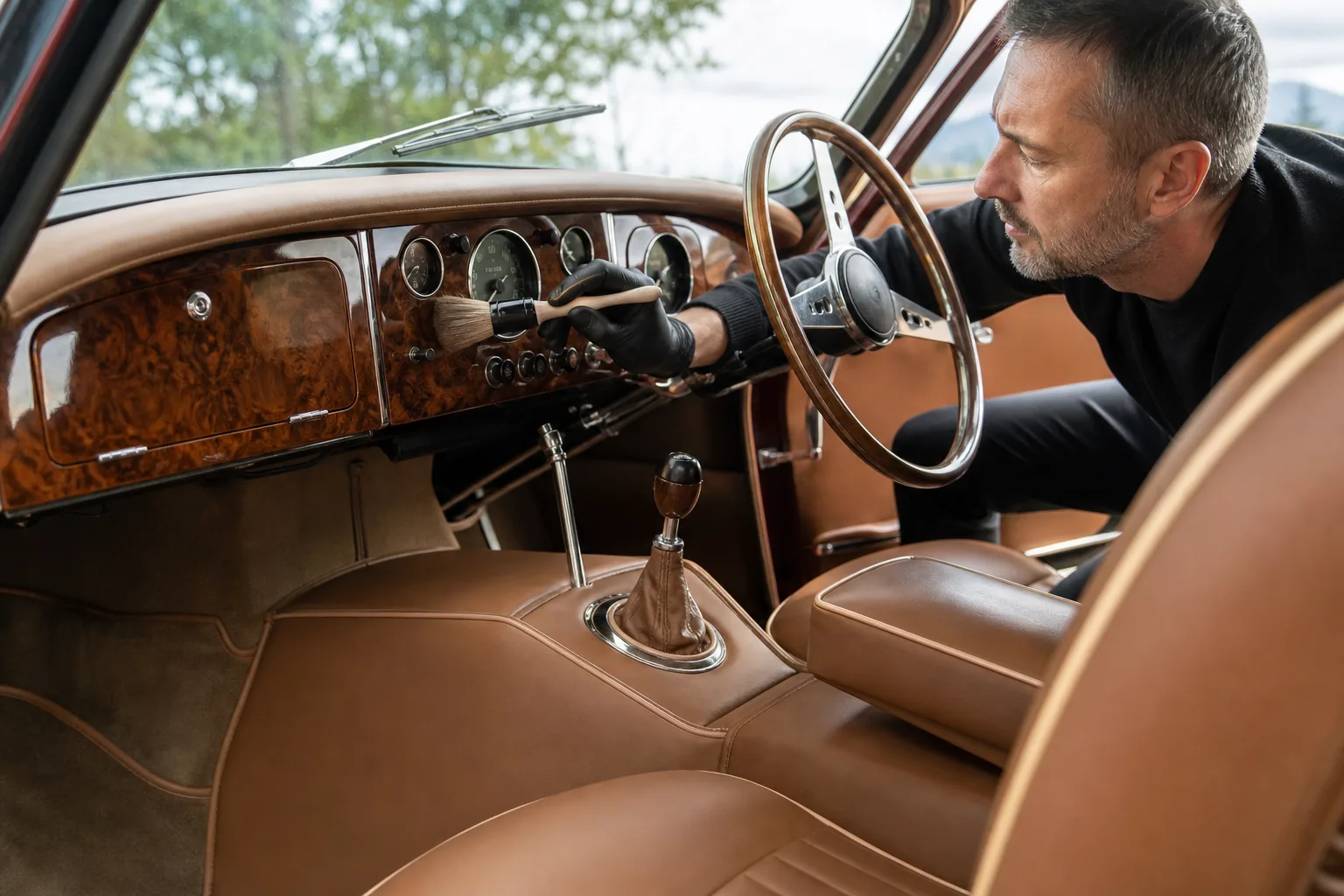 Detailer cleaning a vintage wood-grain dashboard and leather interior during classic car detailing in Las Vegas