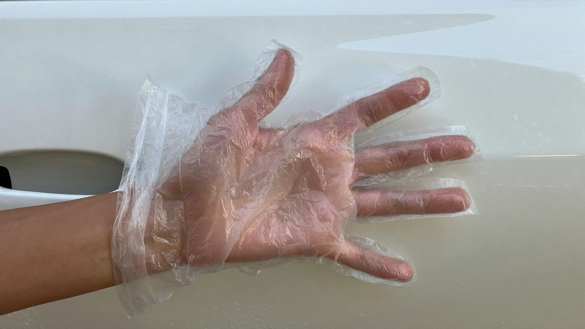 Hand in a plastic bag feeling car paint for rough contamination