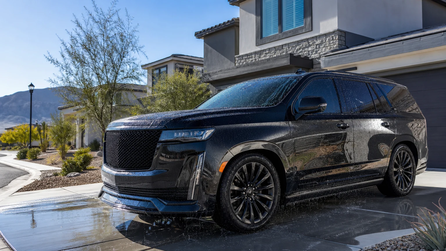 Glossy black SUV with a fresh ceramic coating showing water beading on the hood, parked in the driveway of a new home in a Centennial Hills master-planned community